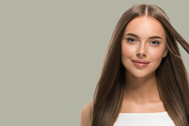 Hermosa mujer con hermoso cabello largo y liso volador en vestido blanco sobre fondo de color verde