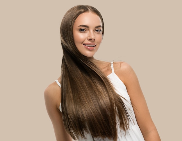 Foto hermosa mujer con hermoso cabello largo y suave con vestido blanco sobre fondo de color