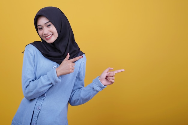 Hermosa mujer con hijab apuntando hacia el lado izquierdo mira feliz expresión