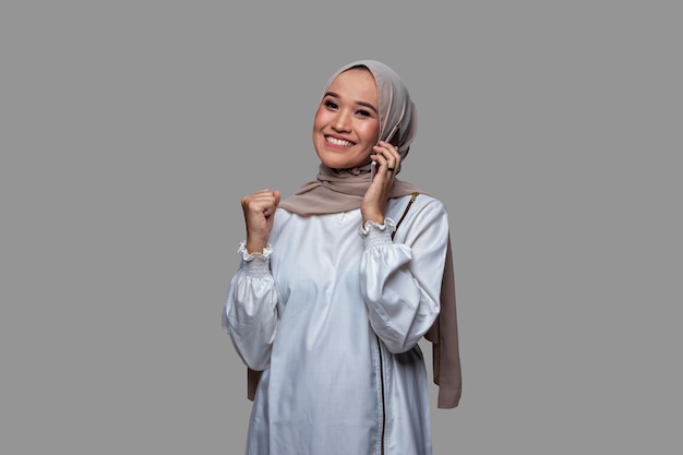 Hermosa mujer con hijab está en la llamada telefónica con una expresión exitosa