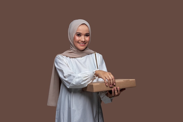 Hermosa mujer con hijab sosteniendo una caja de pizza con ambas manos mientras sonríe