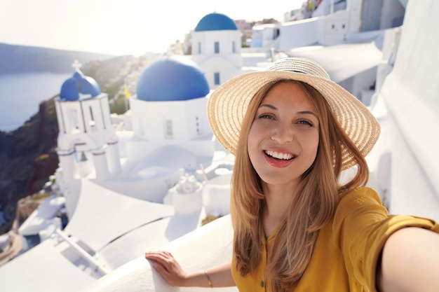Hermosa mujer hispana de moda tomando autorretrato al atardecer en la isla de Santorini Grecia