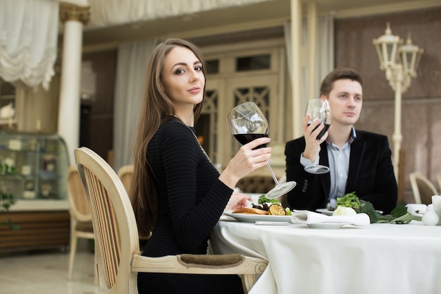 Hermosa mujer y hombre en restaurante, sosteniendo una copa de vino