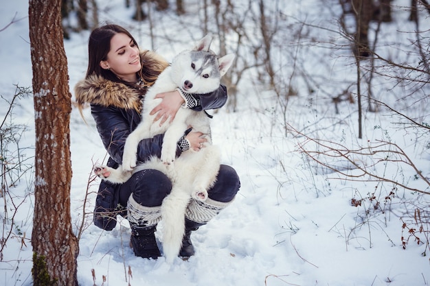 Hermosa mujer con un Husky posando en el invierno