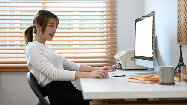 Hermosa mujer independiente creativa que trabaja en línea con una computadora en una oficina en casa moderna y brillante