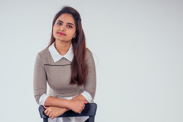 Hermosa mujer india con camisa blanca con cuello y suéter con cabello negro castaño en fondo blanco de estudio