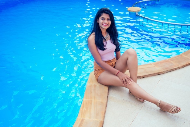 Hermosa mujer india con dientes blancos sonrisa selfie retrato en la cámara del teléfono inteligente café de verano por mar junto a la piscina goa