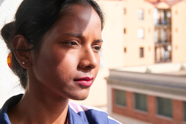 Hermosa mujer india mirando por la ventana soleada