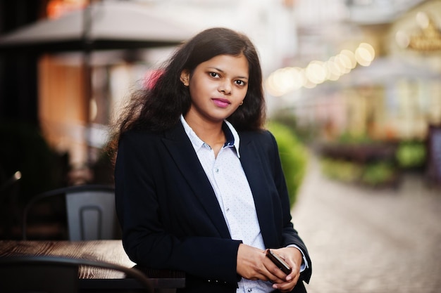 Hermosa mujer india usa una pose formal en la calle con el teléfono móvil en las manos