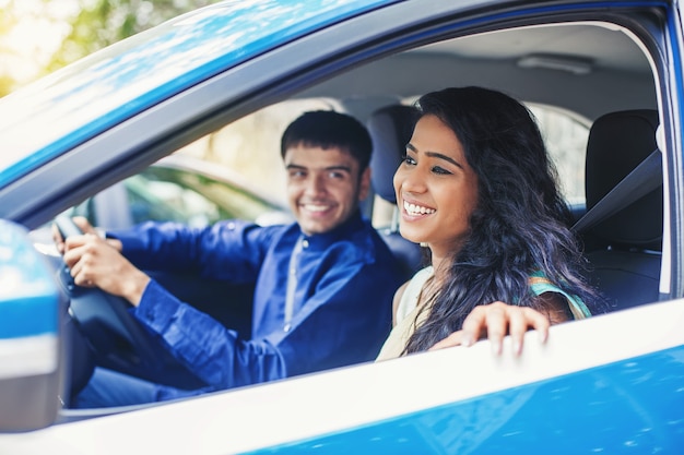 Hermosa mujer india viajando en un coche azul con conductor