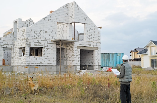 Hermosa mujer ingeniera está de pie en serio frente a un sitio de construcción