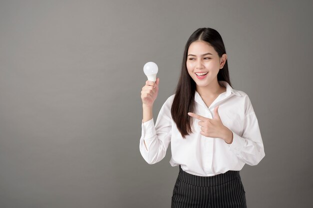 Hermosa mujer inteligente sostiene bombilla