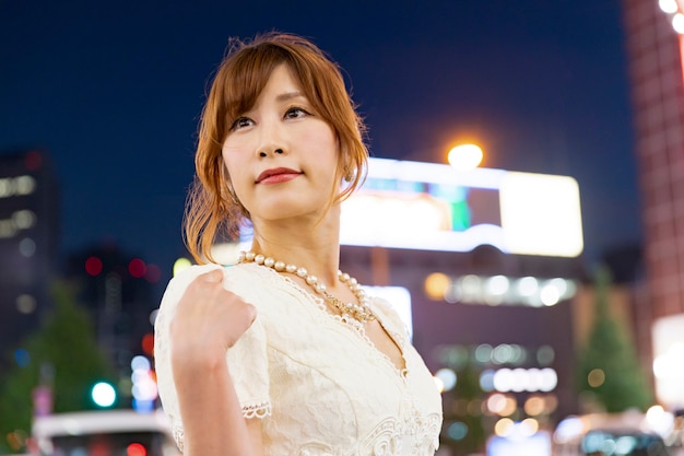Hermosa mujer japonesa con glamoroso vestido blanco en las calles de Tokio, Japón