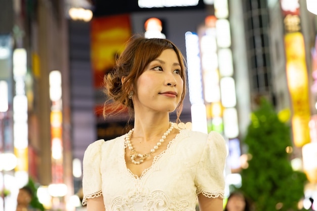 Hermosa mujer japonesa con glamoroso vestido blanco en las calles de Tokio, Japón