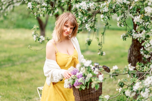 Foto hermosa mujer en un jardín en flor en primavera con una bicicleta retrato de una chica rubia.