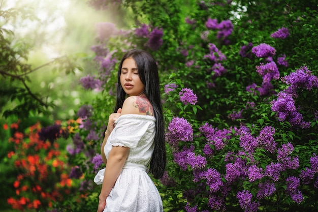 Hermosa mujer en un jardín de primavera bajo un árbol floreciente