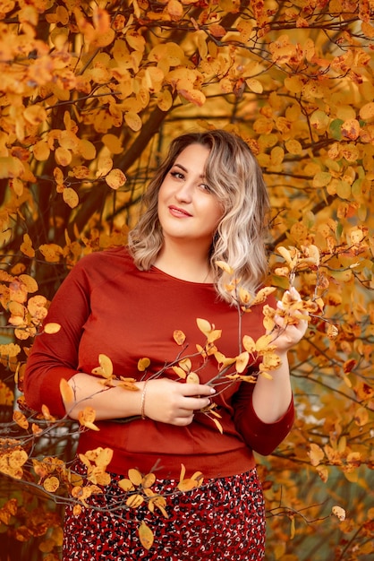 Hermosa mujer joven en un abrigo camina en un parque de otoño Golden Autumn Landscape