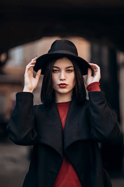 Hermosa mujer joven en un abrigo negro y sombrero