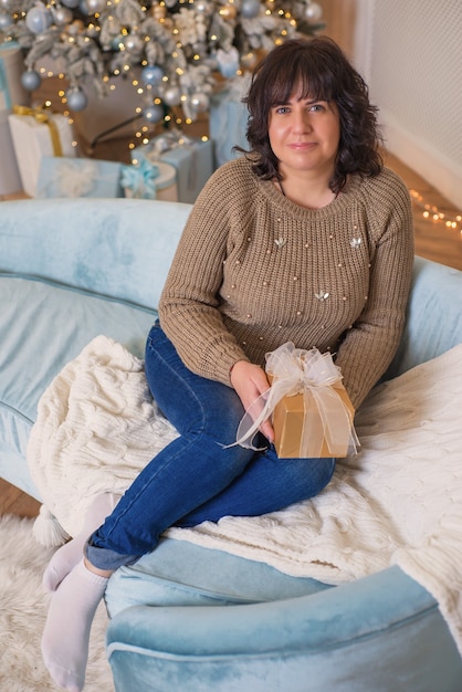 Hermosa mujer joven en una acogedora casa celebra el retrato de Navidad cerca del árbol