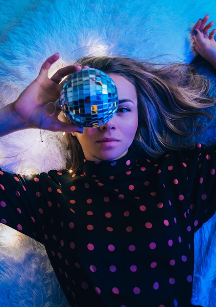 Foto hermosa mujer joven acostada con bola de discoteca. concepto de fiesta. año nuevo navidad o fiesta de cumpleaños. felices alegres y sueños mágicos. divirtiéndose