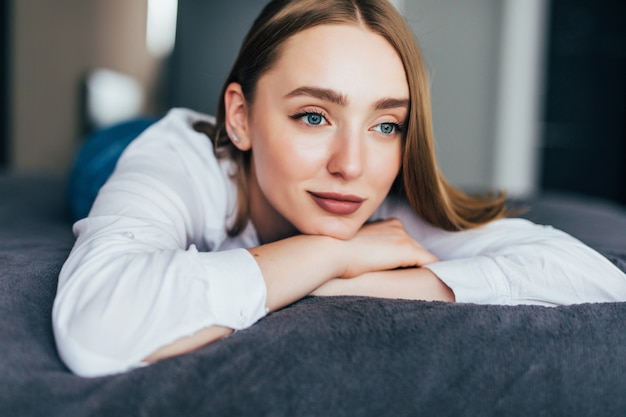 Hermosa mujer joven acostada en la cama en casa