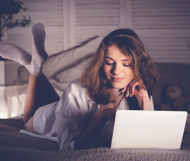 Hermosa mujer joven acostada en la cama con cuaderno