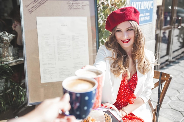 Hermosa mujer joven al aire libre. Atractiva jovencita sentada en la cafetería bebiendo café.