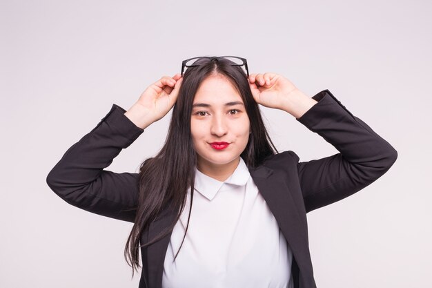 Hermosa mujer joven asiática morena con gafas en la pared blanca.