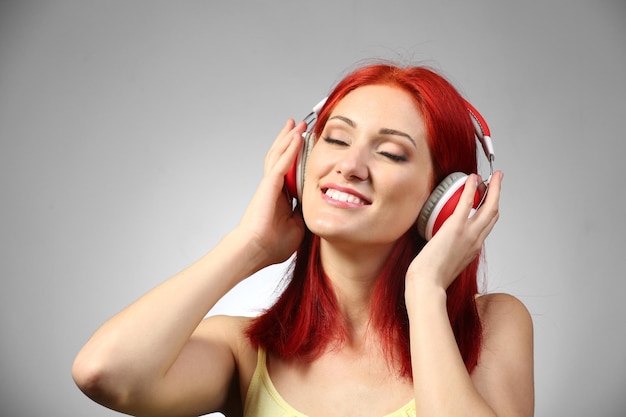 Hermosa mujer joven con auriculares sobre fondo gris