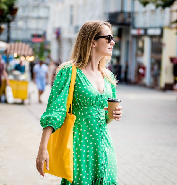 Hermosa mujer joven con bolsa ecológica de lino amarillo sobre fondo de ciudad
