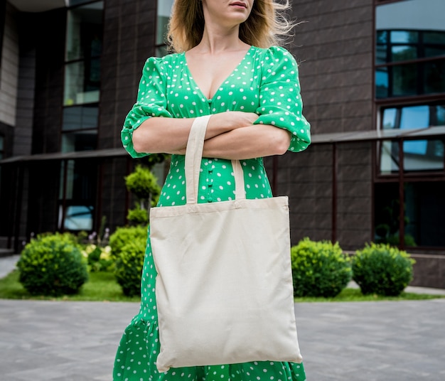 Hermosa mujer joven con bolsa ecológica de lino en el fondo de la ciudad