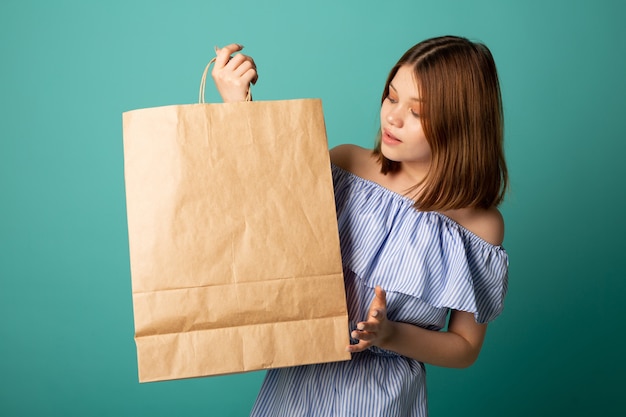 Hermosa mujer joven con bolsa de papel en la mano con cara de sorpresa