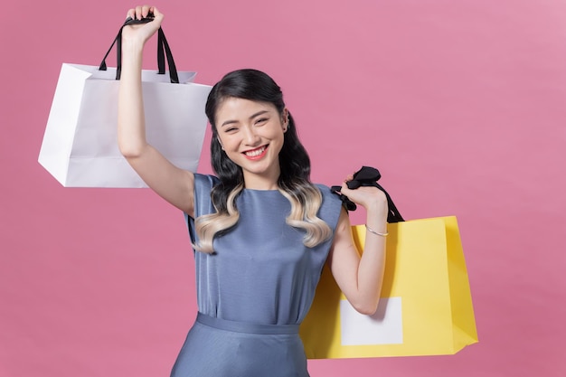 Hermosa mujer joven con bolsas de la compra sobre fondo de color