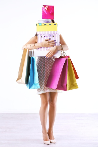 Hermosa mujer joven con bolsas de compras y cajas aisladas en blanco