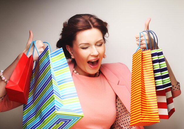 Foto hermosa mujer joven con bolsas de compras de colores sobre fondo gris