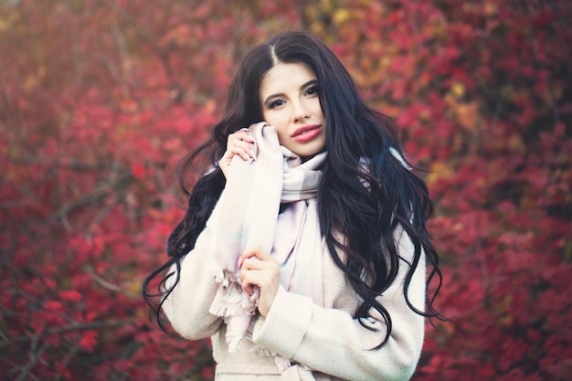 Hermosa mujer joven con cabello largo y moreno en el parque de otoño al aire libre