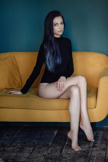 Hermosa mujer joven con cabello negro y azul y un cuello de tortuga negro posando en una elegante habitación Estudio de moda disparó Moda retro