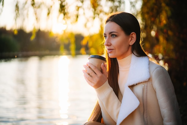 Hermosa mujer joven con café en el parque Bonito estilo de vida de otoño dama relajante