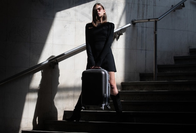 Hermosa mujer joven en la calle de la ciudad. Hermosa joven mujer de moda. Viajar con maleta.