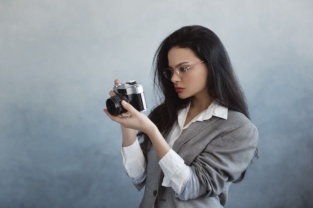 Hermosa mujer joven con cámara de fotos en el interior. Retrato de chica joven fotógrafo de moda