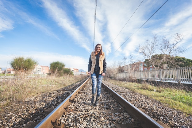 Hermosa mujer joven caminando sobre las vías del tren.