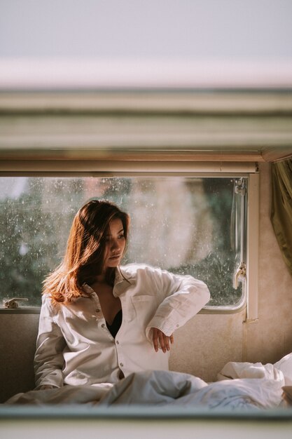 Hermosa mujer joven con una camisa blanca en el dormitorio en casa