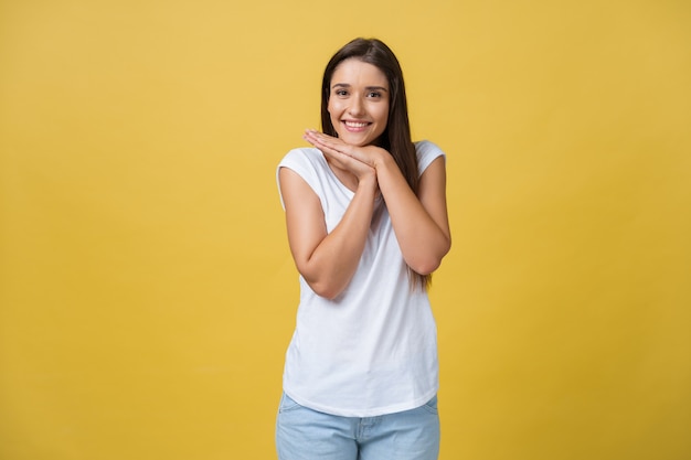 Hermosa mujer joven con camisa blanca está sosteniendo la cabeza entre las manos, sonriendo y mirando a la cámara.