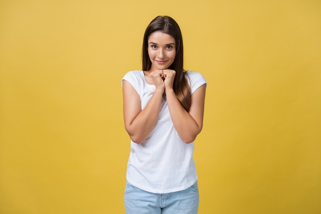 Hermosa mujer joven con camisa blanca sostiene la cabeza en las manos sonriendo y mirando a la cámara