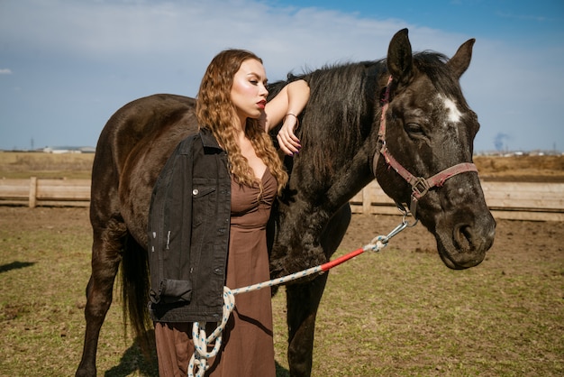 Hermosa mujer joven en un campo con caballos. Modelo de moda atractiva.