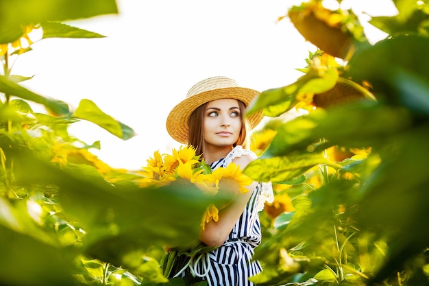 Hermosa mujer joven en campo de girasol en verano