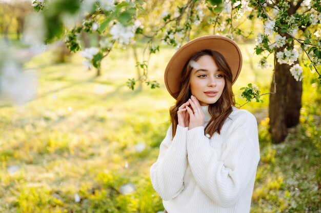 Hermosa mujer joven cerca del árbol de primavera floreciente Concepto romántico de amor juvenil