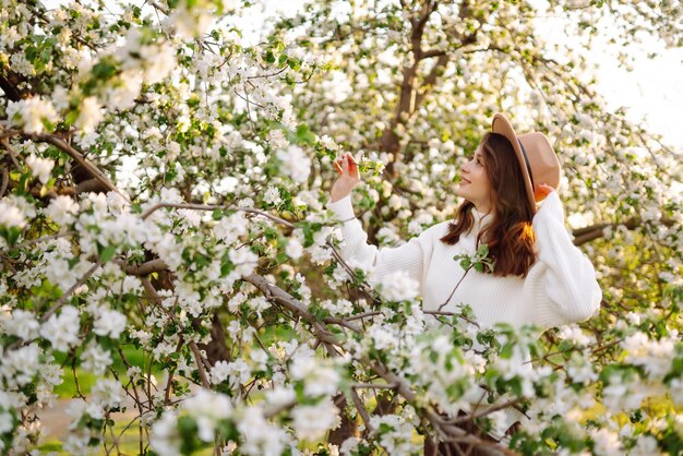 Hermosa mujer joven cerca del árbol de primavera floreciente Concepto romántico de amor juvenil