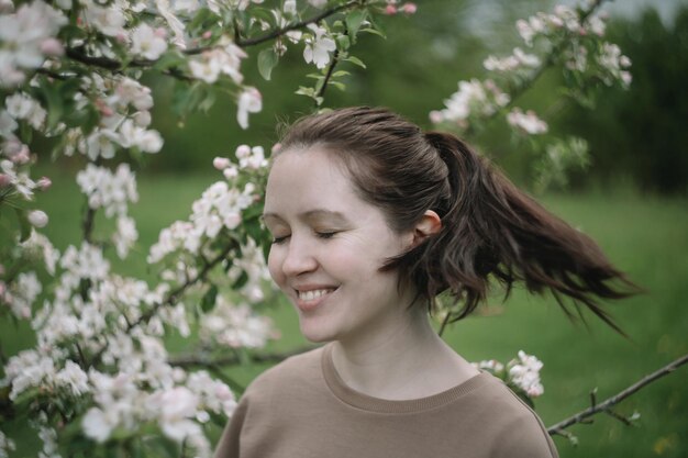 Hermosa mujer joven cerca del floreciente árbol de primavera Amor juvenil Moda romántica y concepto de estilo de vida