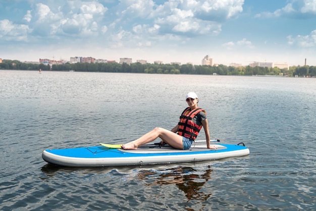 Hermosa mujer joven en un chaleco protector aprende a nadar en el ático en un lago de la ciudad